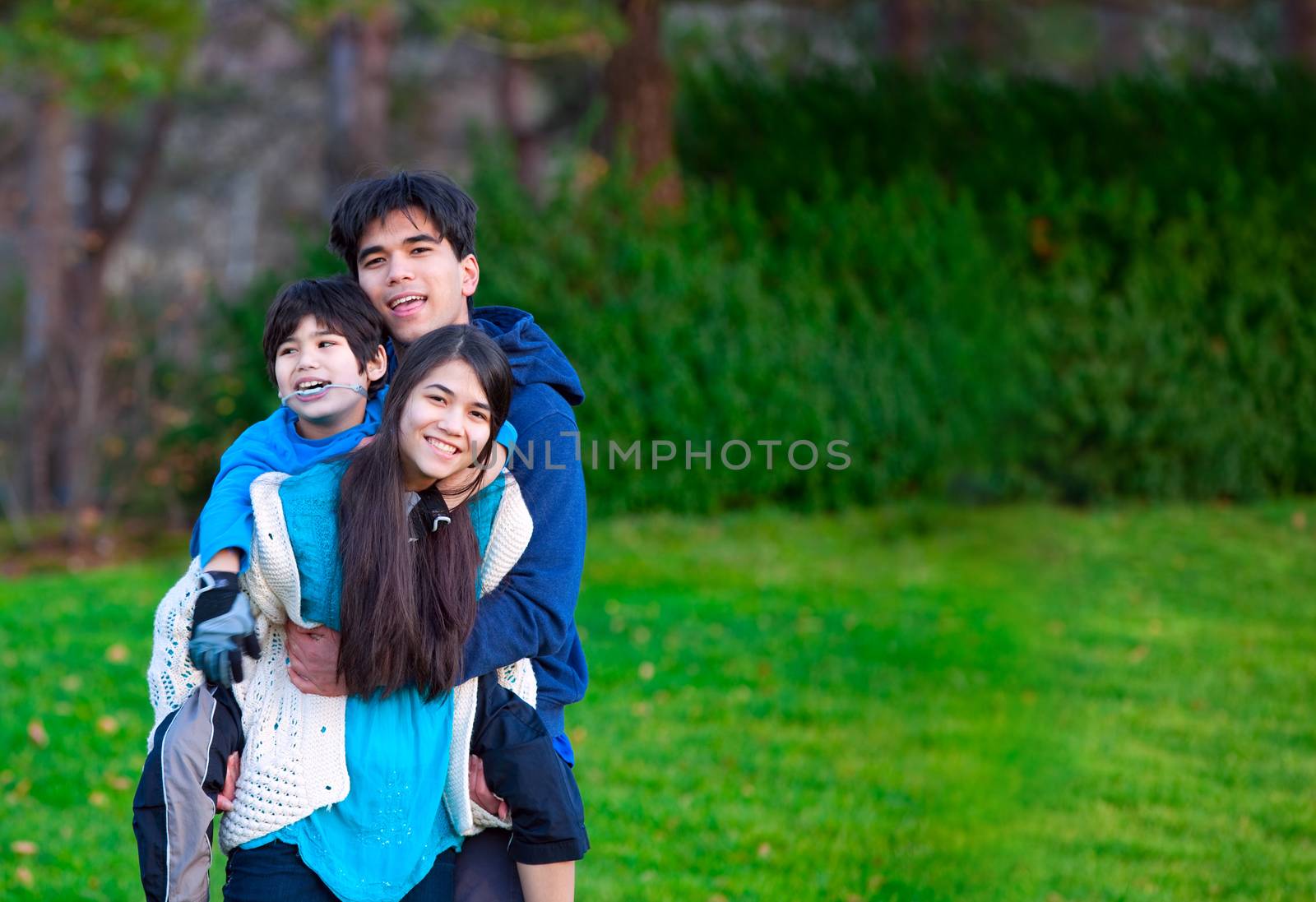 Disabled biracial child riding piggy back on his sister, family  by jarenwicklund