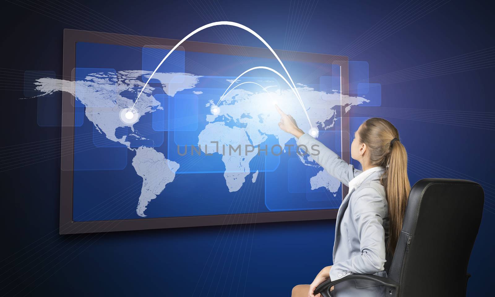 Businesswoman operating touch screen interface featuring world map with flight paths or trade routes or communication between countries and cities and on blue background