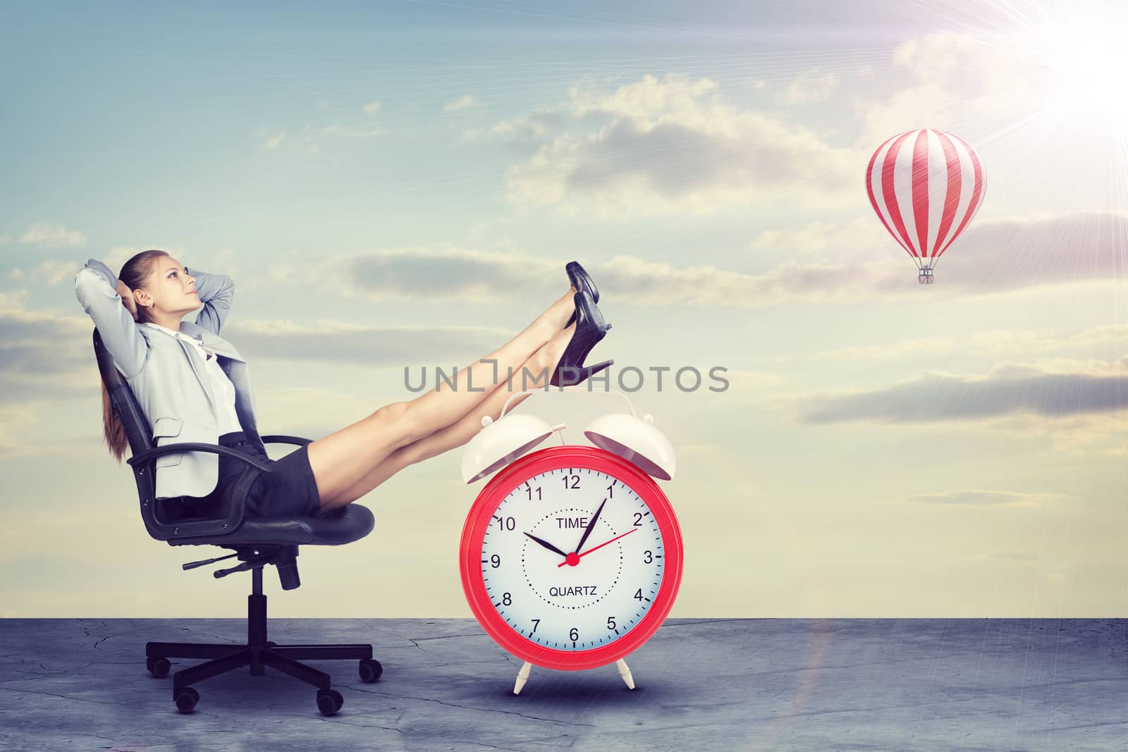 Businesswoman sitting with her feet up on alarm-clock  by cherezoff