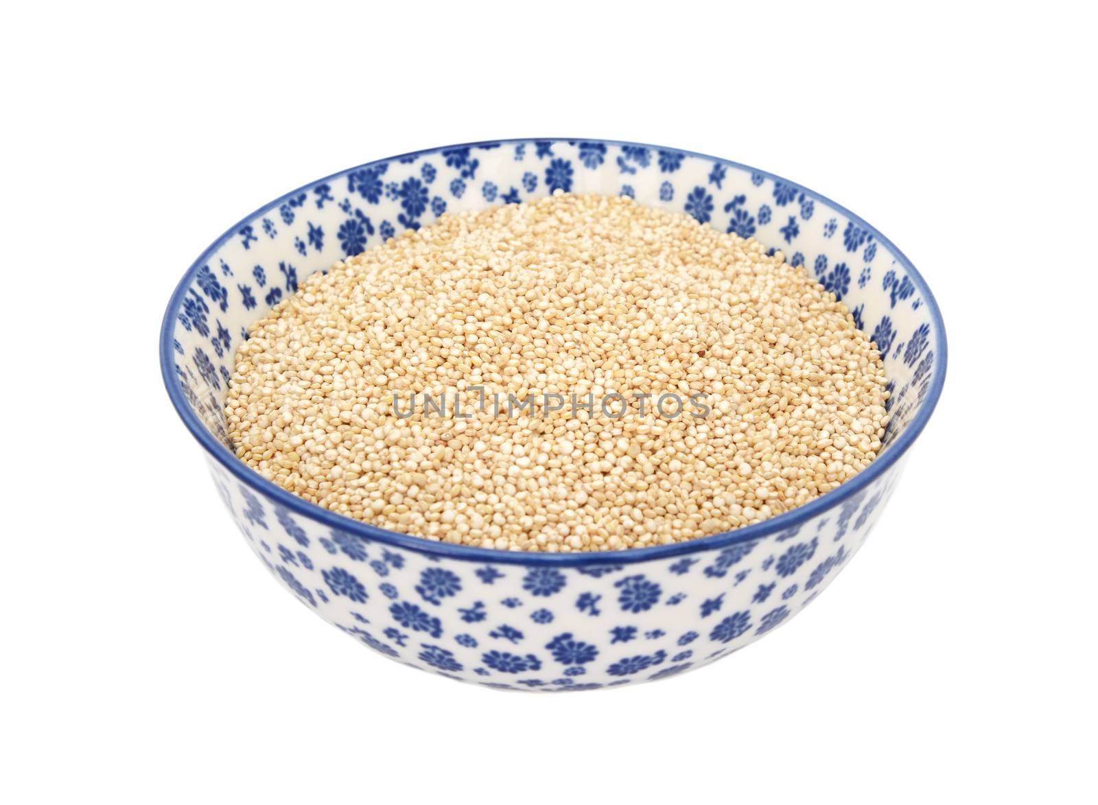 Quinoa in a blue and white porcelain bowl with a floral design, isolated on a white background