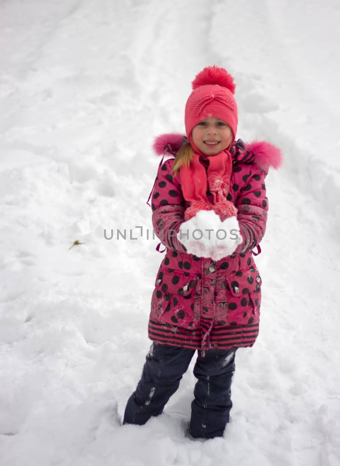 Little girl in winter pink hat in snow.