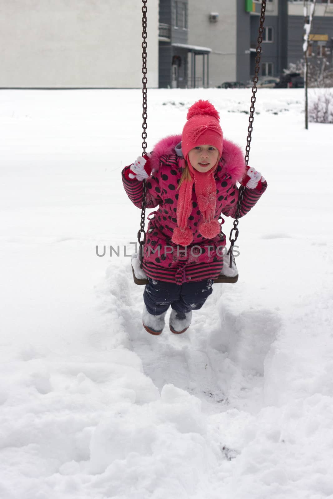 Adorable girl having fun on a swing on beautiful winter day