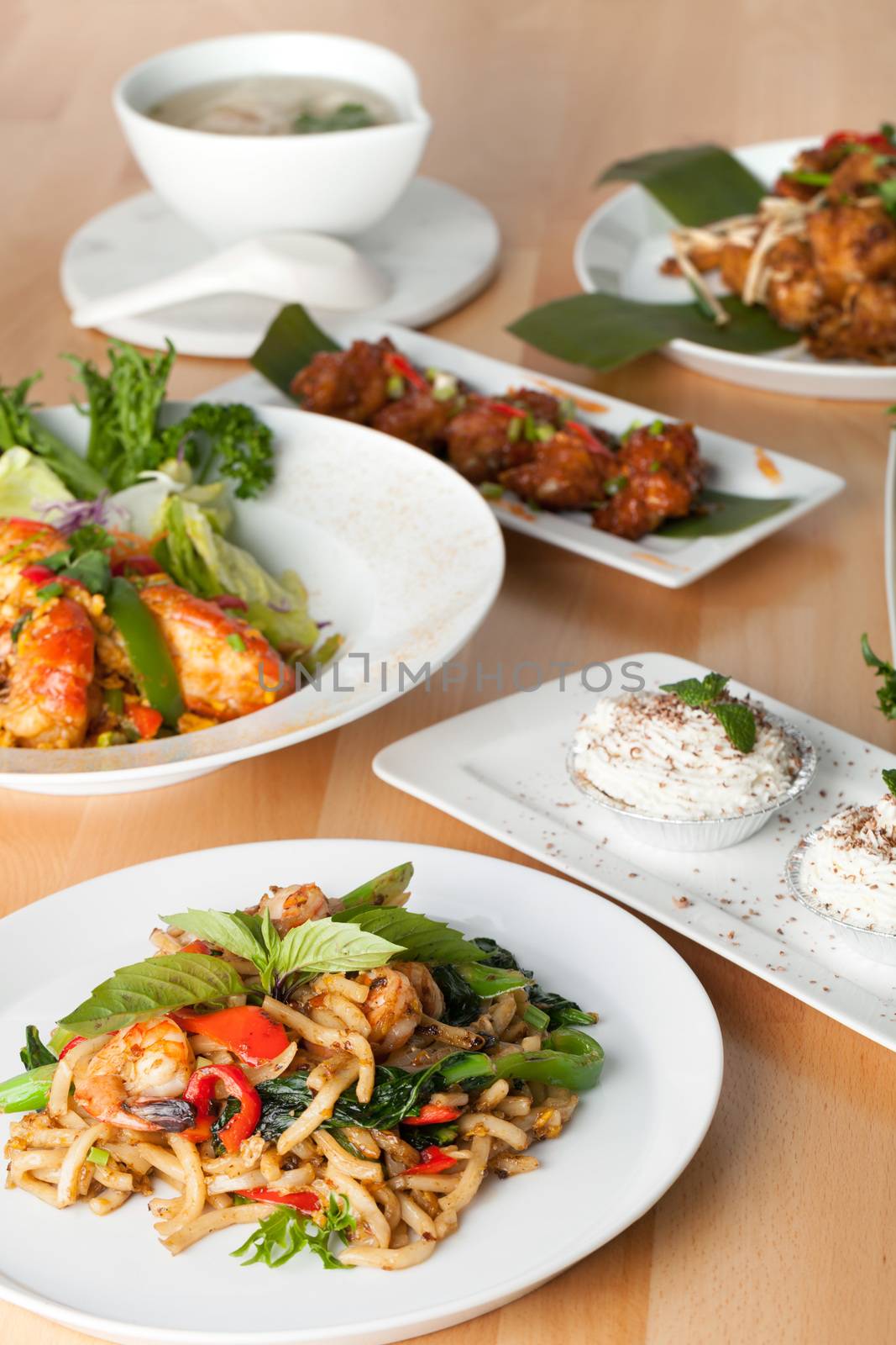 Varieties of Thai foods and appetizers covering a table. Shallow depth of field.