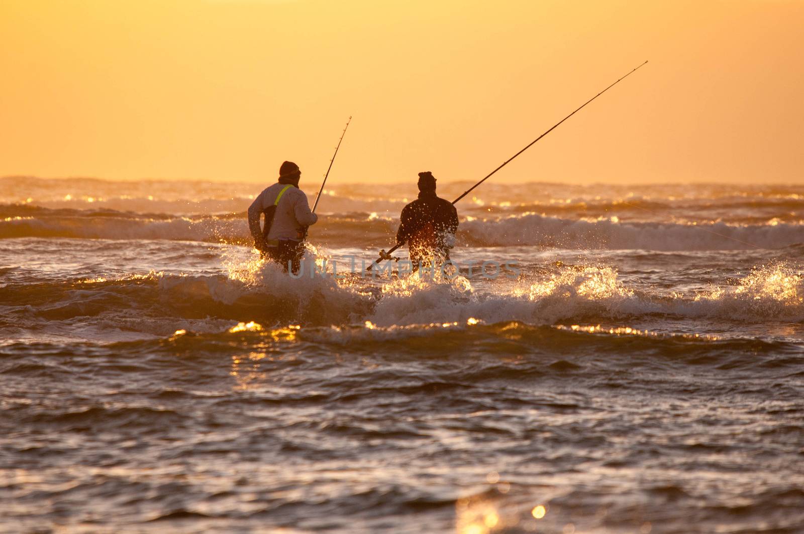 CAPE TOWN, SOUTH AFRICA - DECEMBER 20TH, 2014: Silhouette of two anglers against sunset at The Strand near Cape Town in the Western Cape Province of South Africa
