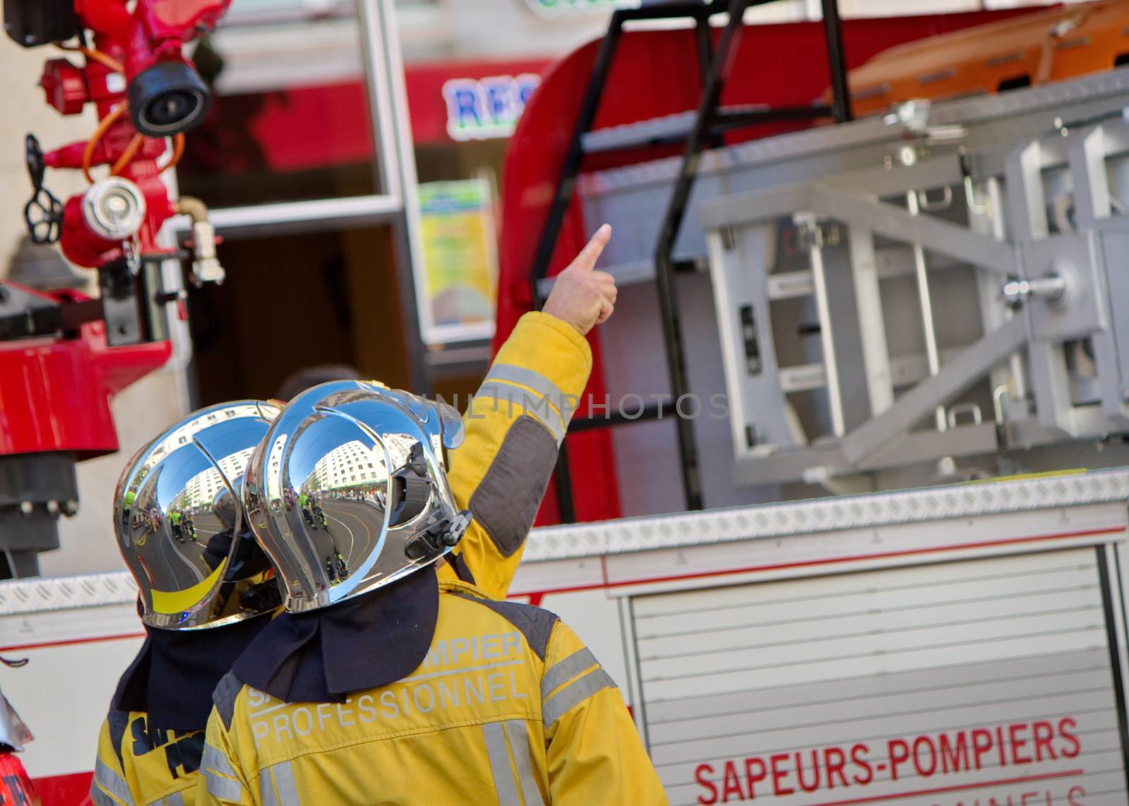 Two firefighters wearing helmets discussing next to fire truck, Geneva, Switzerland