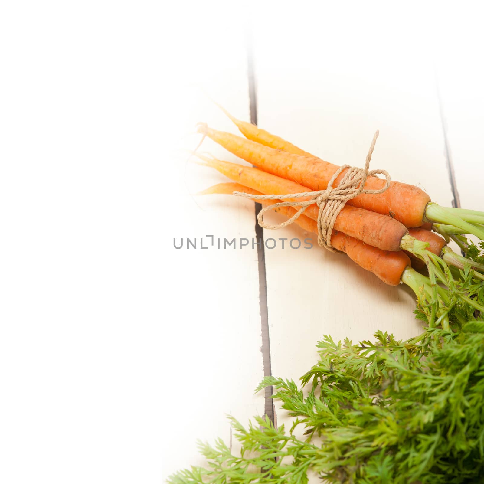 fresh baby carrots bunch tied with rope on a rustic table