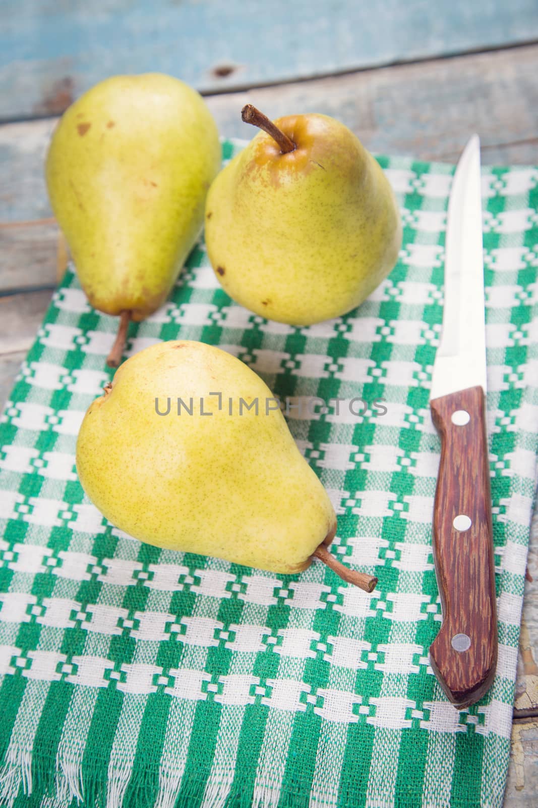 three raw ripe pears on wooden background in studio
