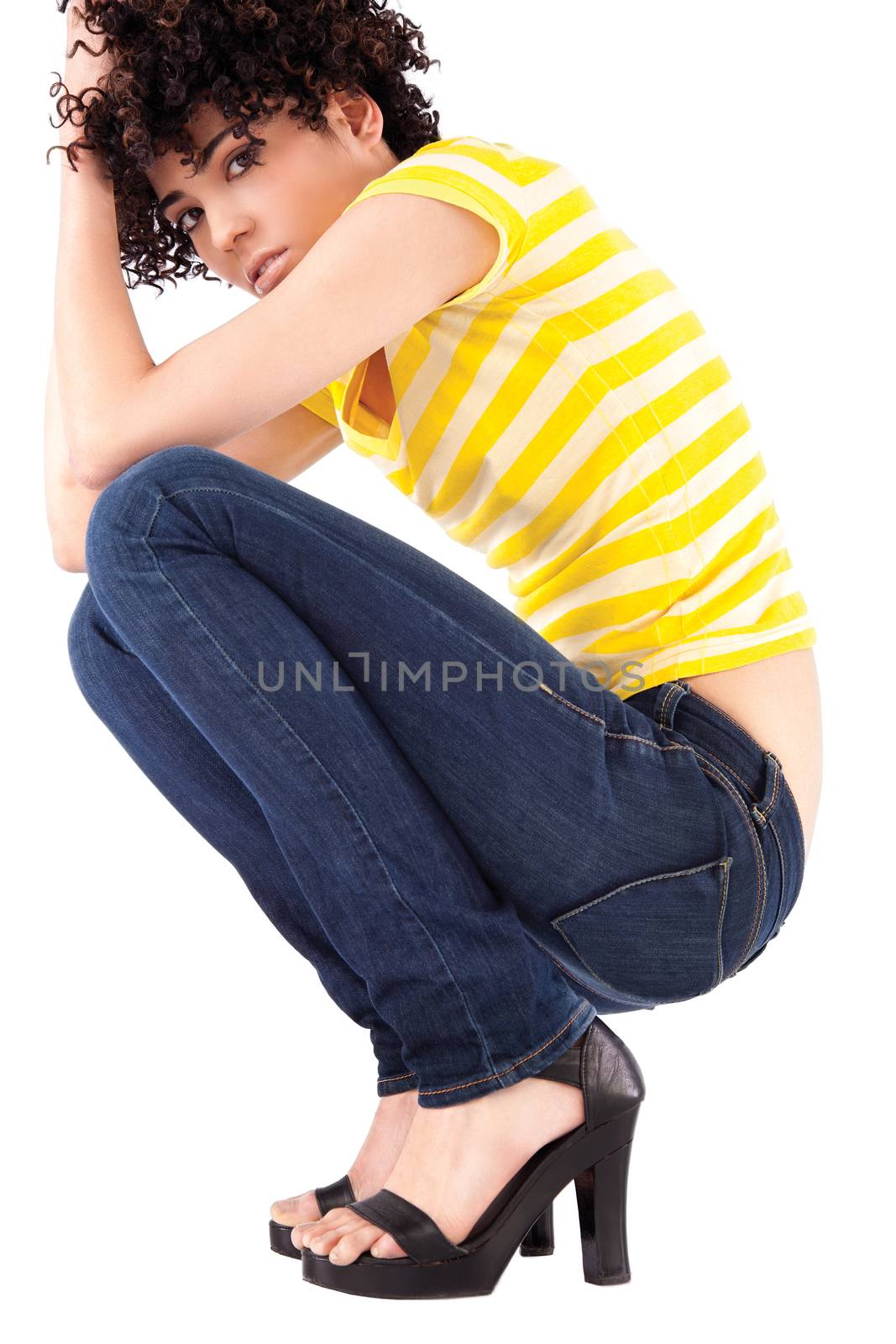 Young woman squatting with curly hair and shirt with yellow stripes.