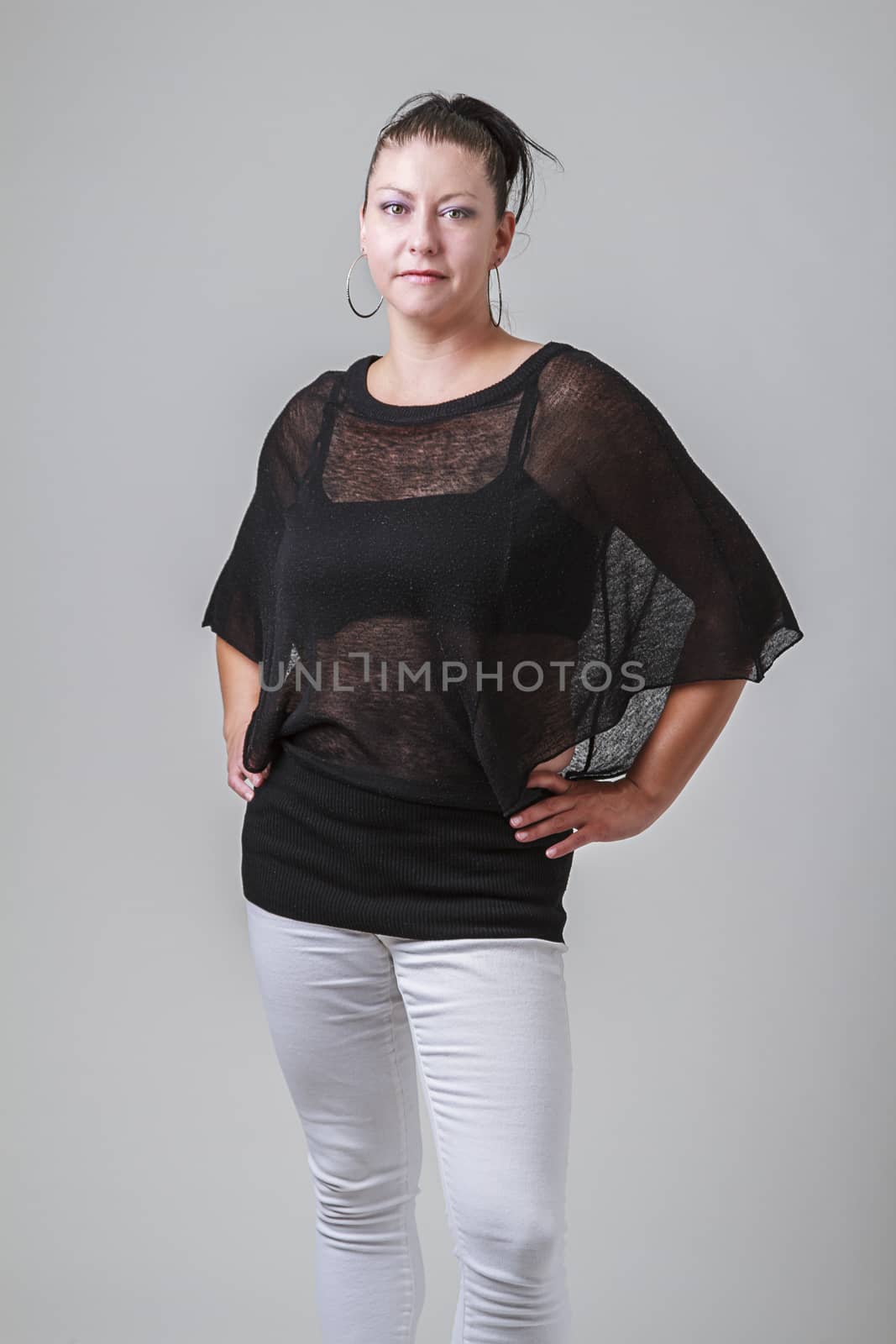 woman in her thirties, wearing a transparent blouse and white pants