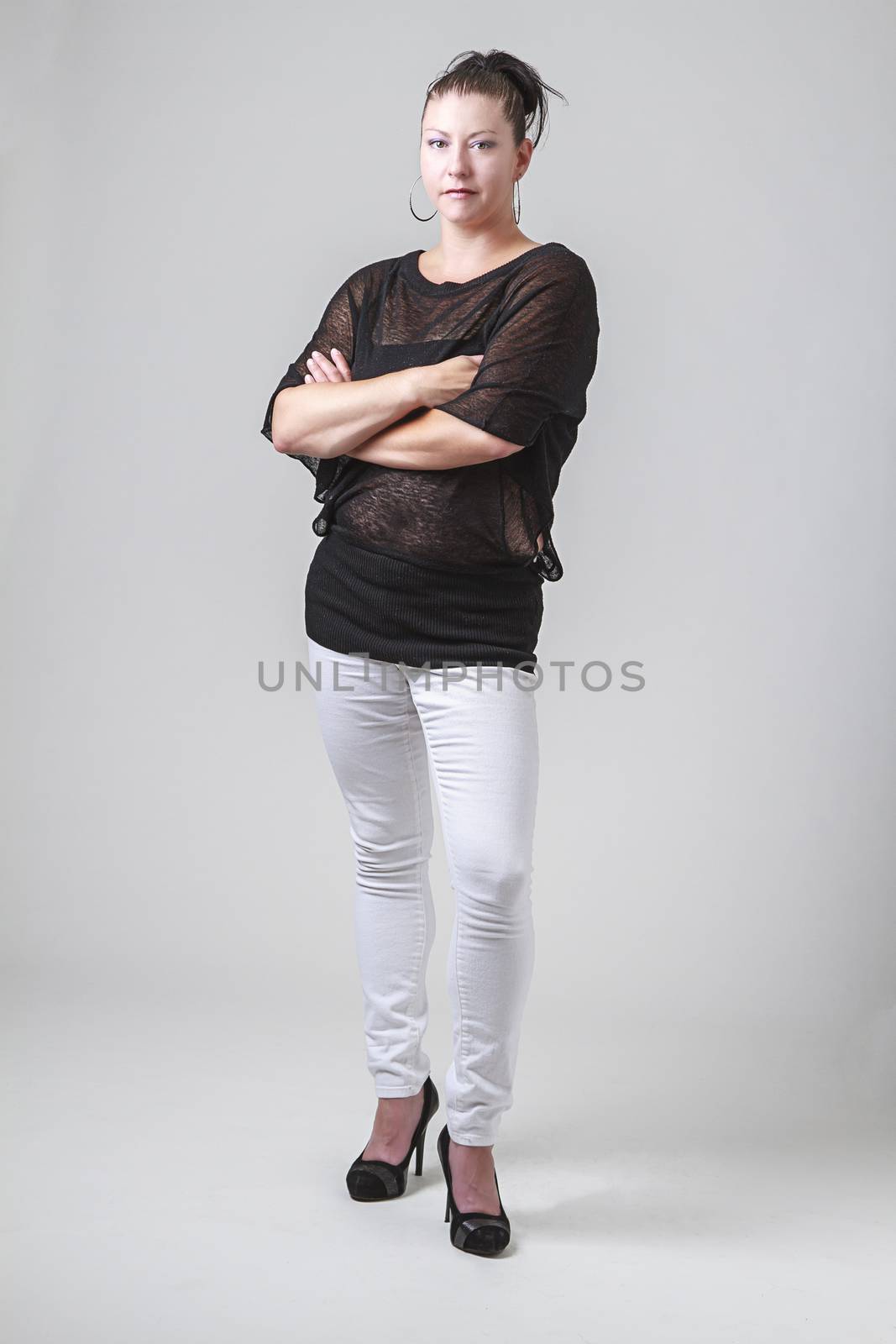 woman in her thirties, wearing a transparent blouse, white pants and high heels