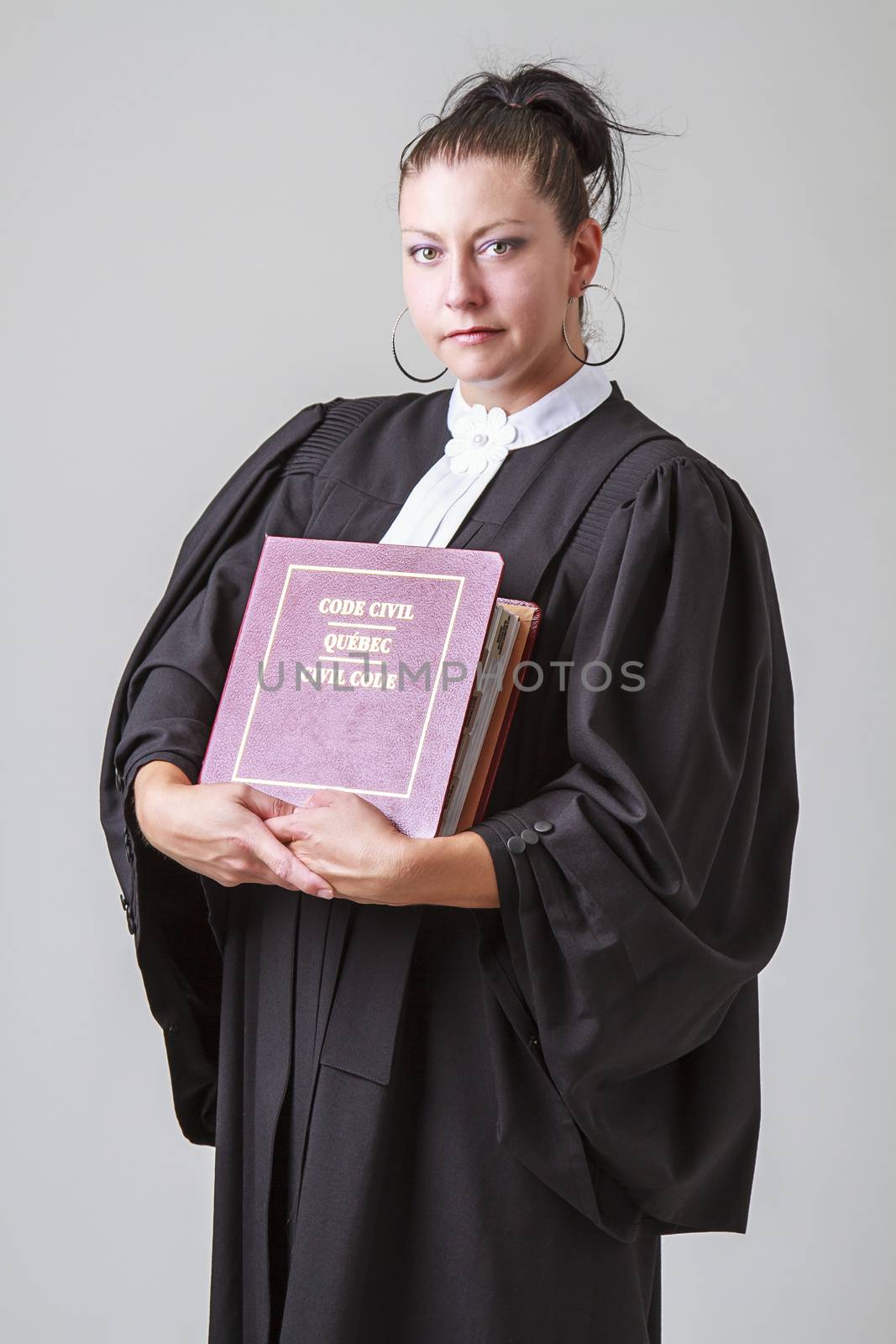 thirty caucasian woman wearing canadian lawyer toga and a red criminal law book