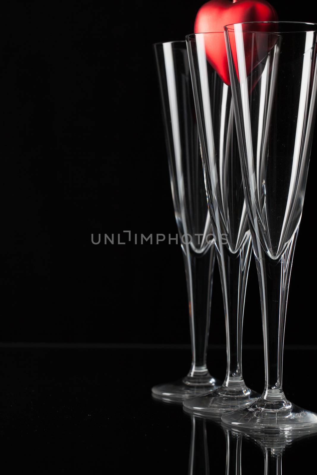 Three champagne glasses and red heart on a glass plate