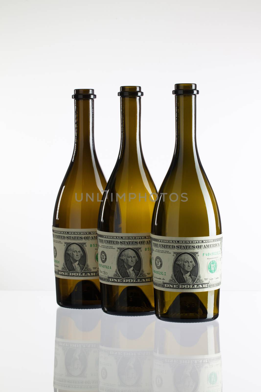 Empty bottles of wine from the label of dollar bill on a glass table
