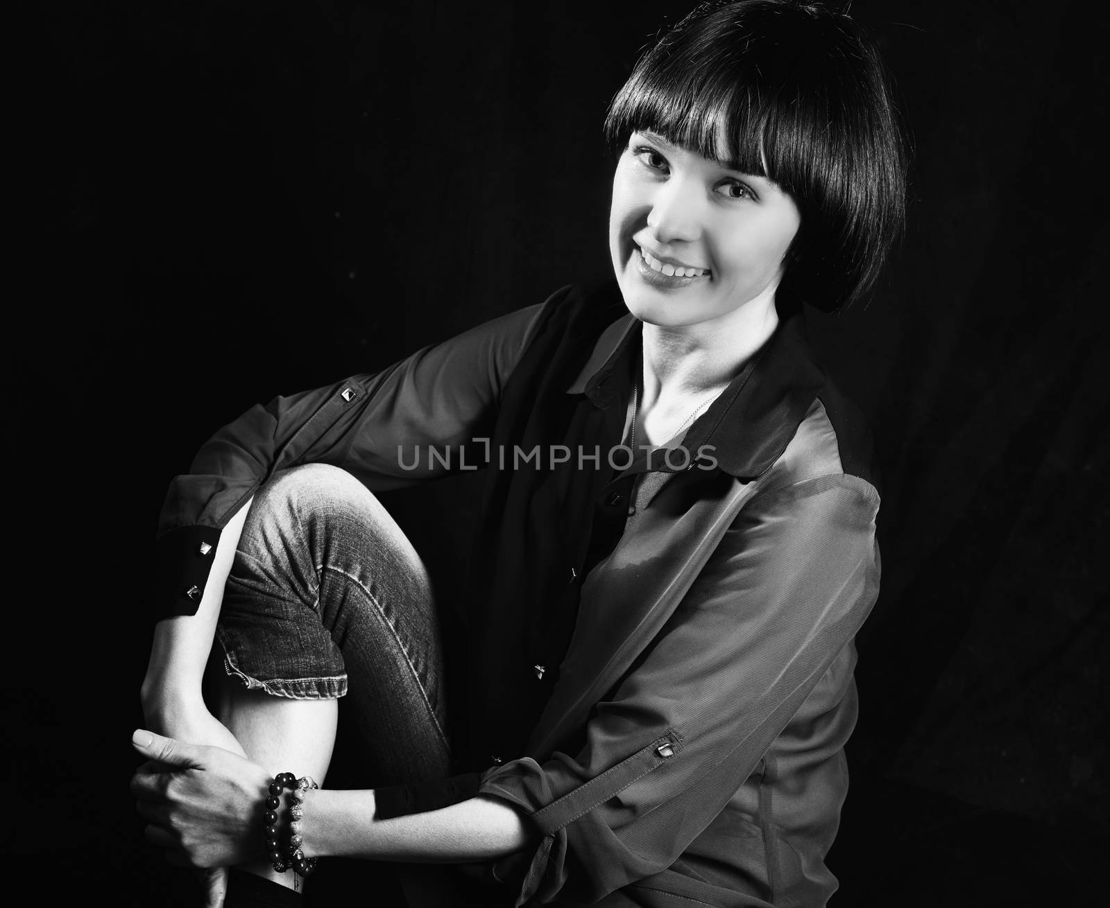 Black and white image of beautiful woman posing in studio on black background