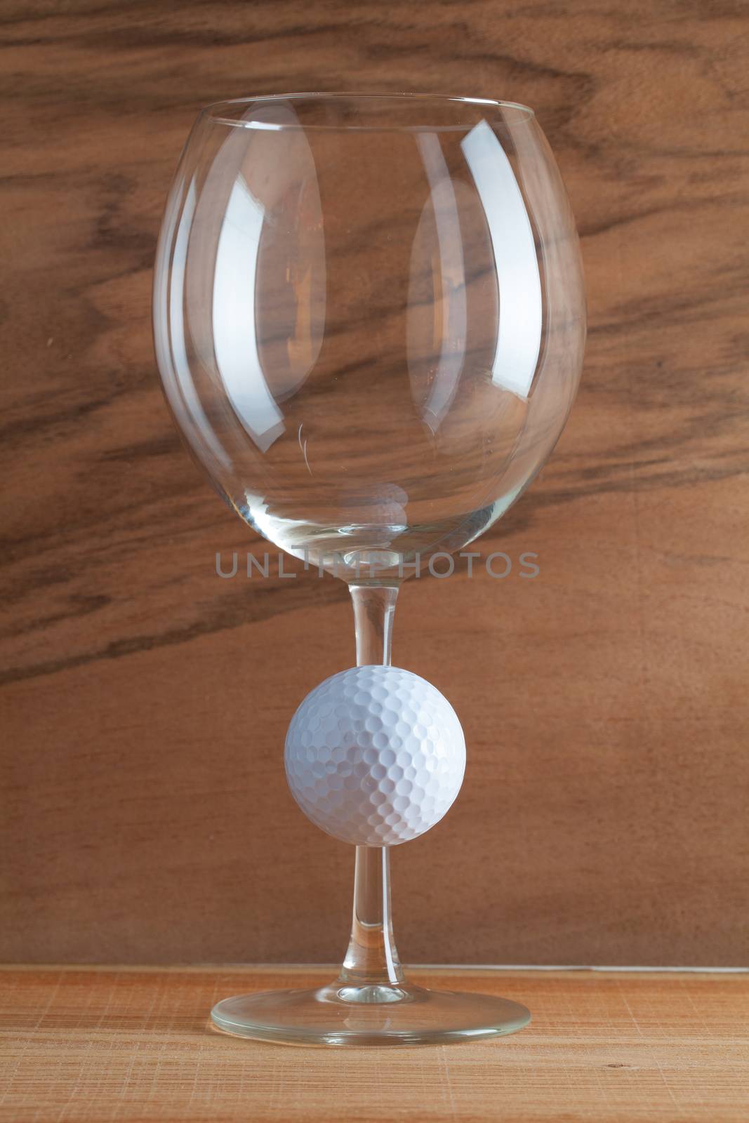 Glass of wine and golf ball on the wooden background from real wood veneer with interesting growth