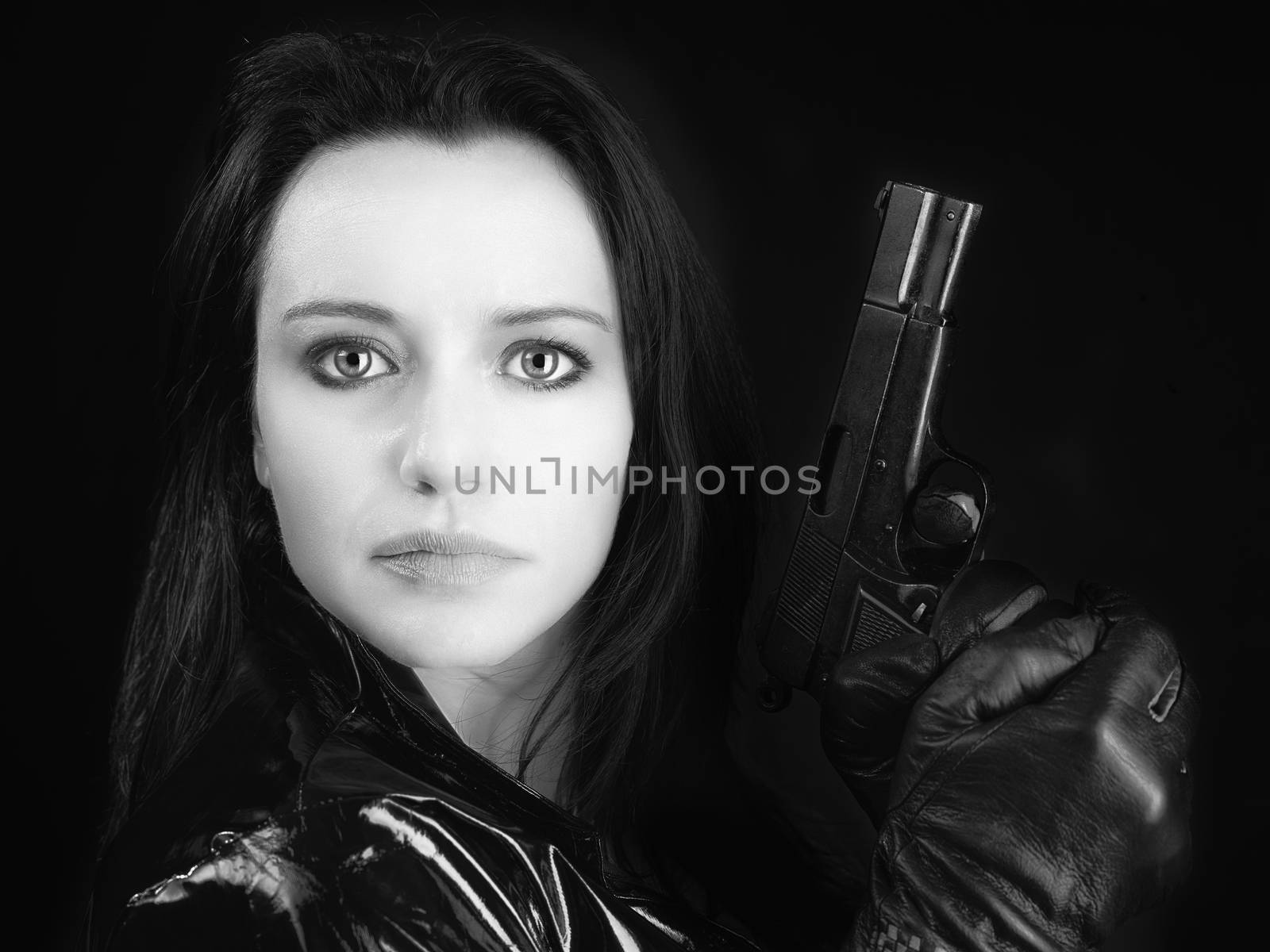 Black and white image of secret agent woman with gun in hand on black background