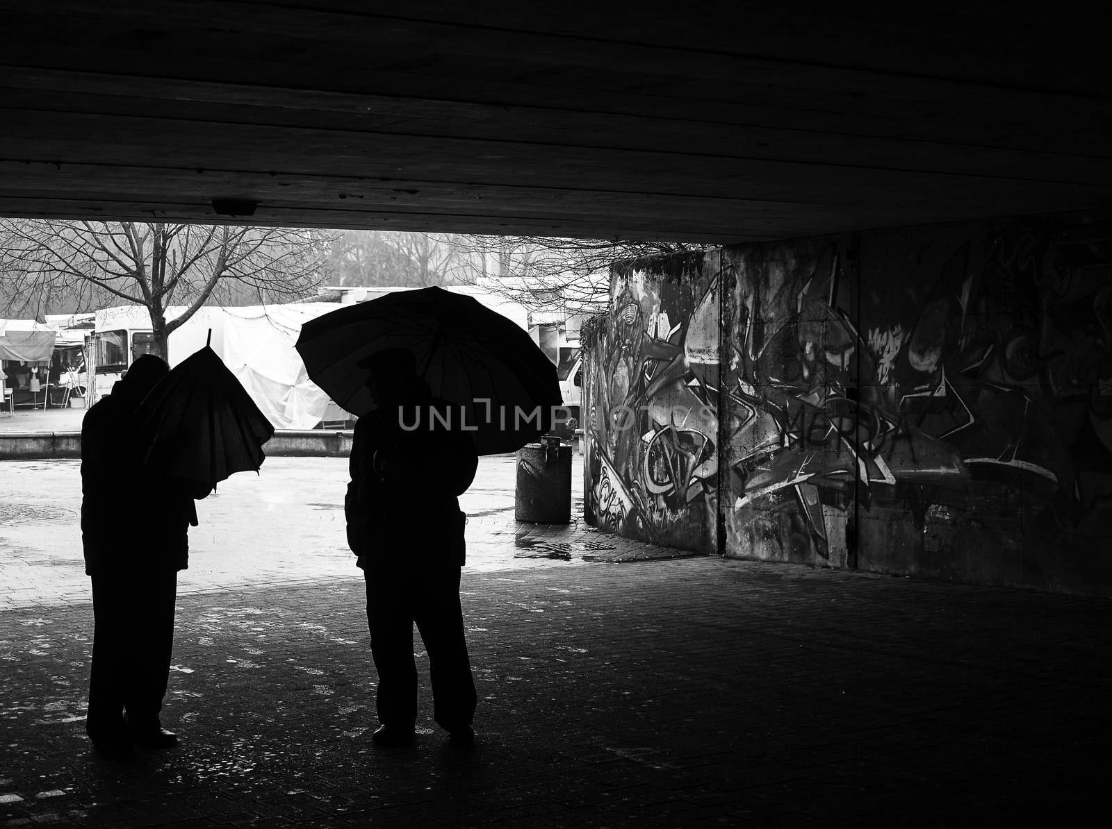 Black and white image of two people with umbrellas outdoor