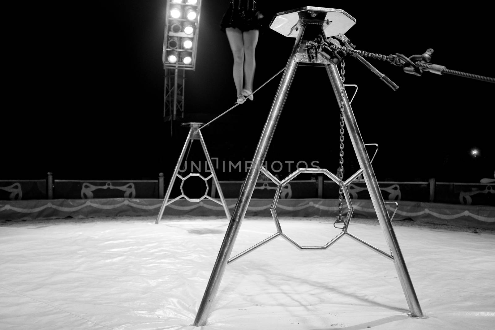 Black and white image of Female acrobat legs performing on horizontal bar