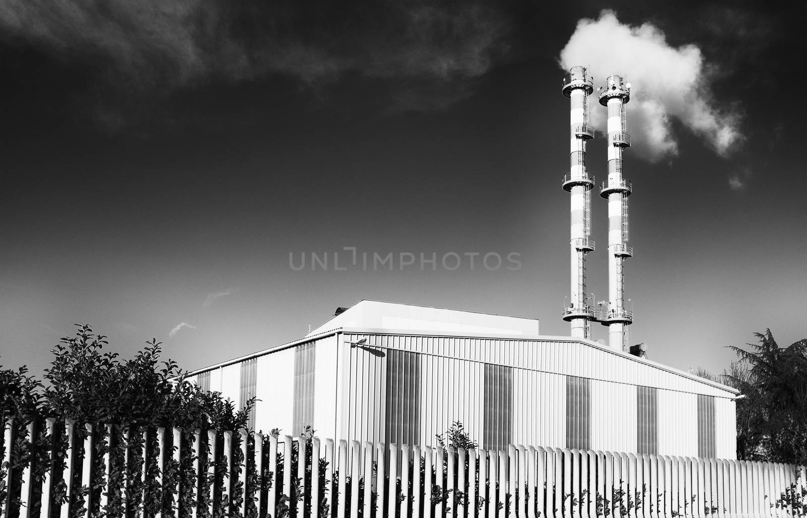 Black and White image of factory with smoke from pipes