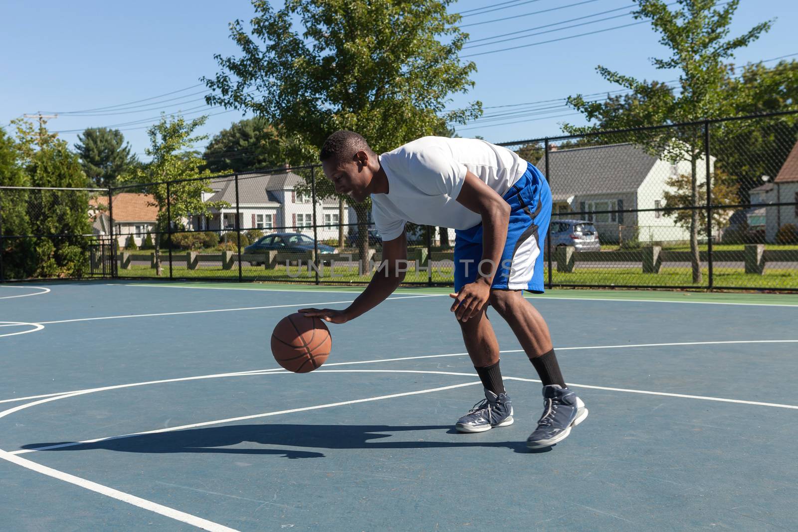 A sweaty young basketball player dribbling down the court demonstrating his ball handling skills.