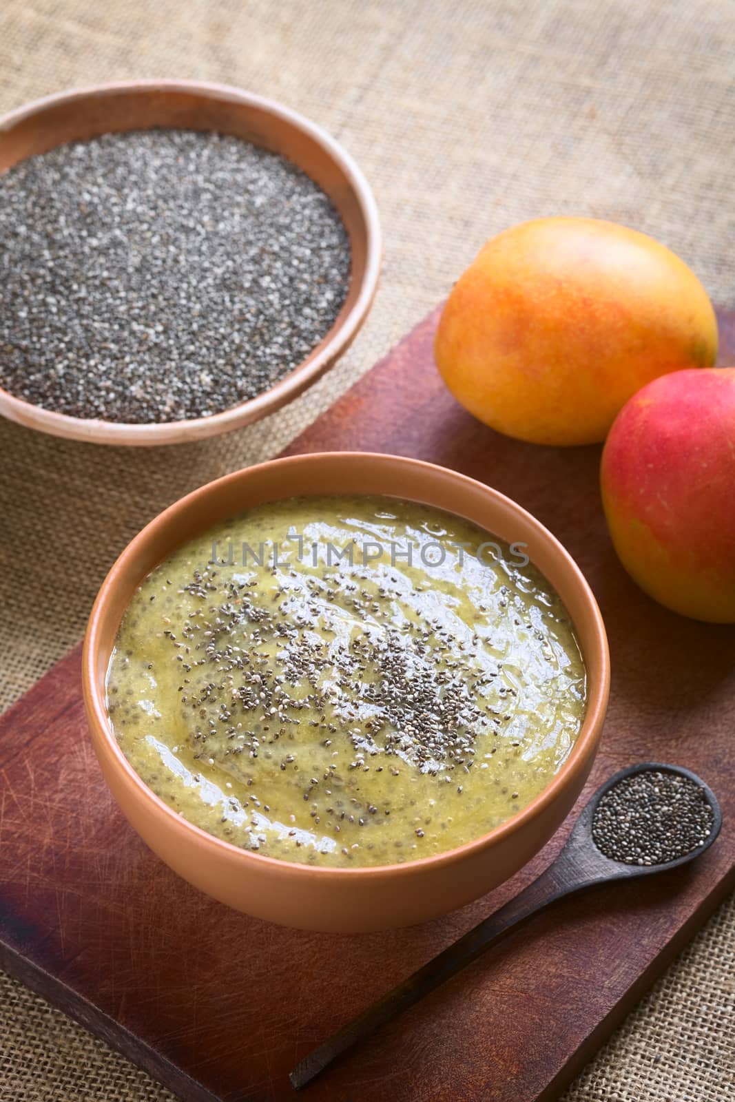 Healthy chia seed (lat. Salvia hispanica) and mango pudding in bowl on wood, photographed with natural light (Selective Focus, Focus in the middle of the pudding)