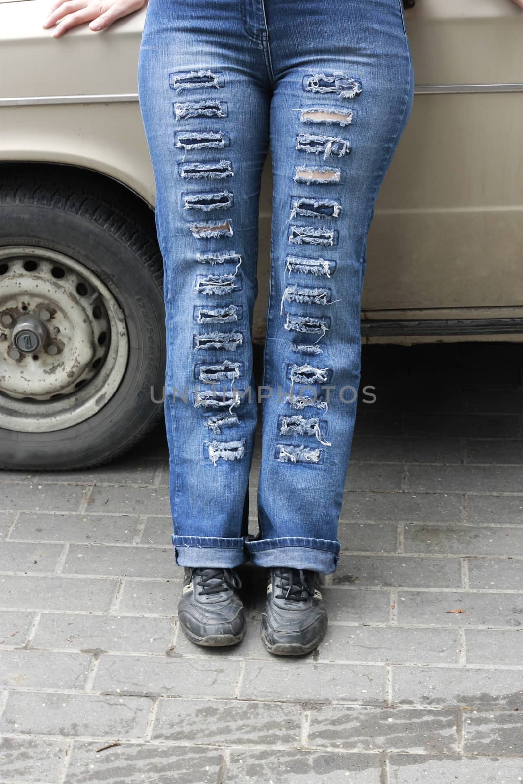 Woman in blue grunge jeans standing near auto