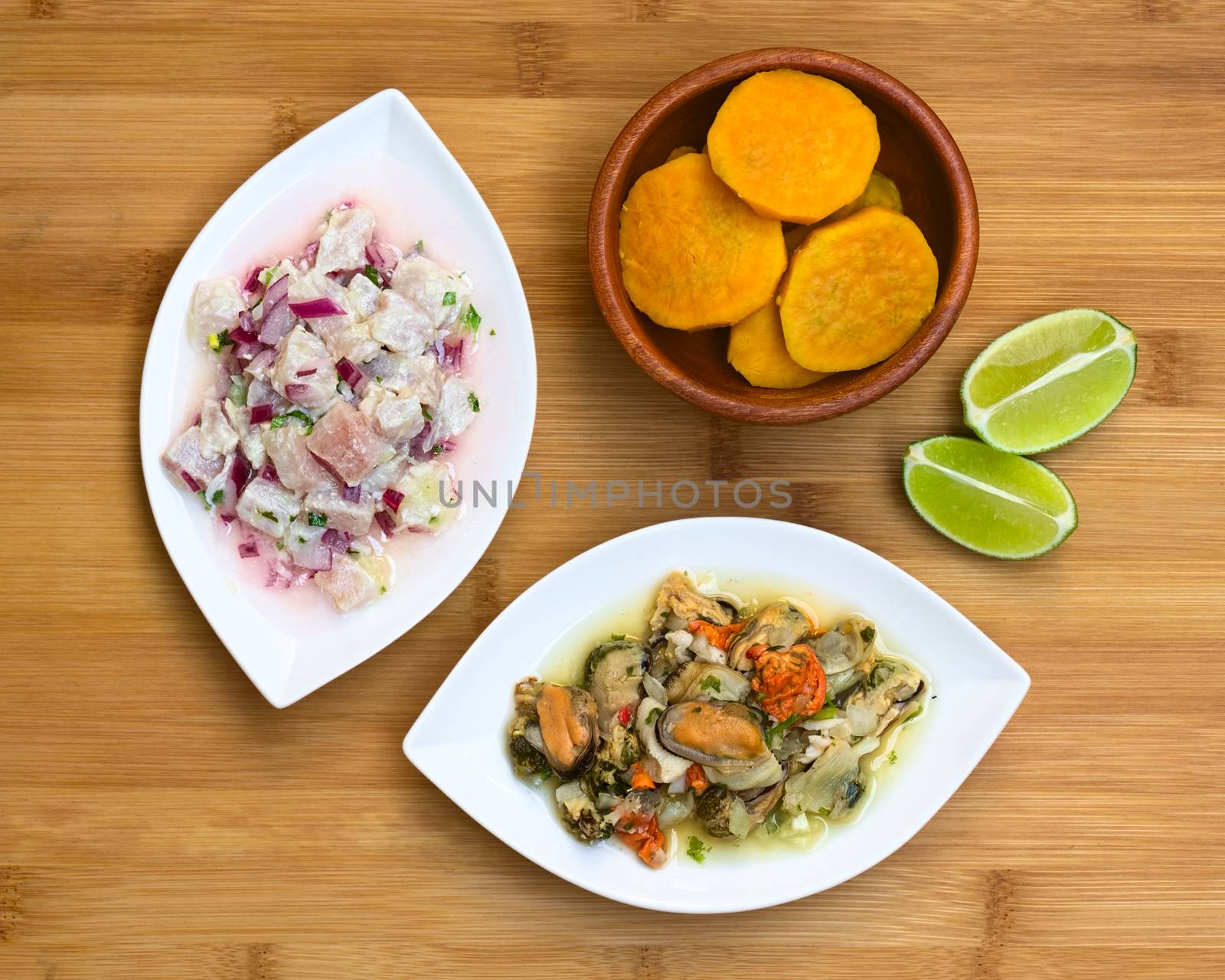 Overhead shot of fish and shellfish ceviche (raw fish and shellfish with red onion marinated in lime juice with garlic, salt and coriander) on wooden board, photographed with natural light