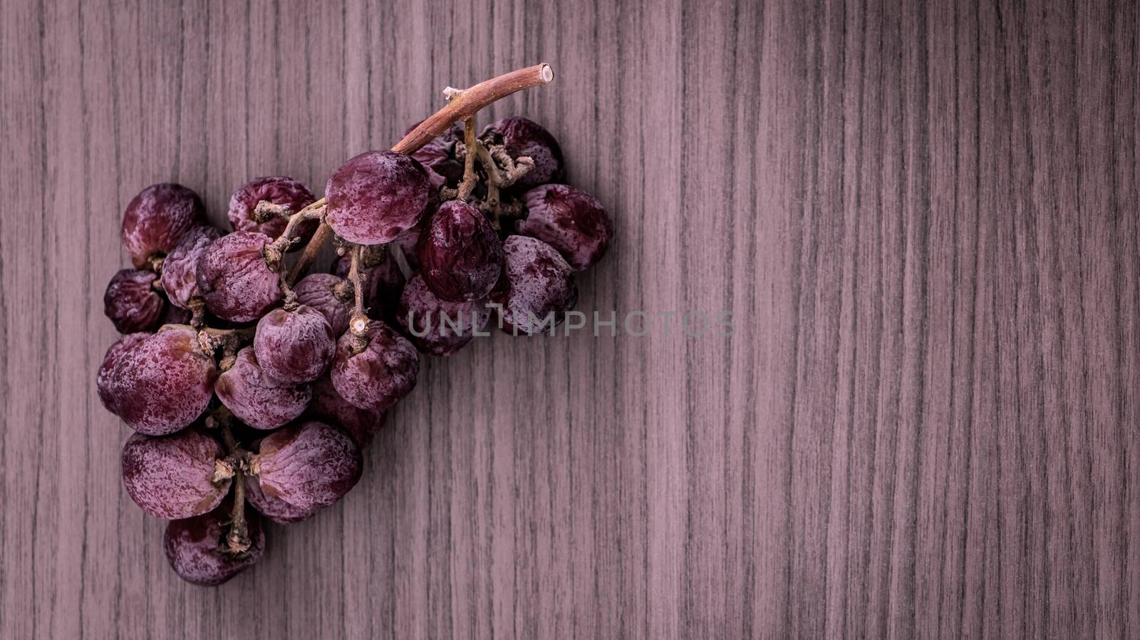 A bunch of overripe red grapes on wood