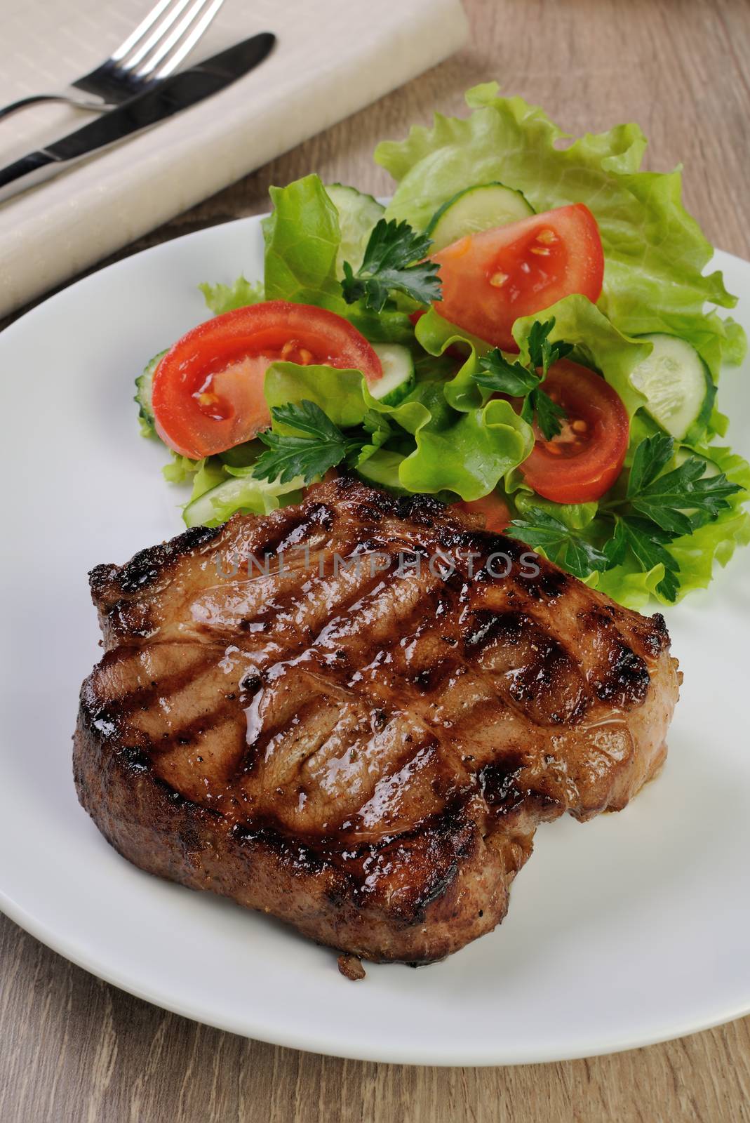 A piece of juicy pork steak grilled with a salad