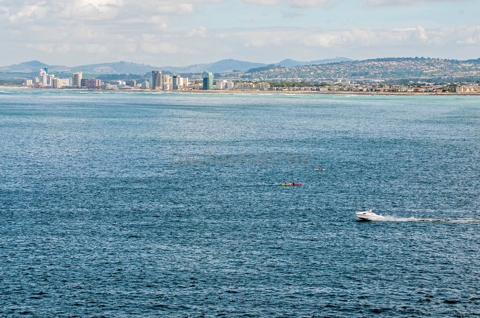 CAPE TOWN, SOUTH AFRICA - DECEMBER 20, 2014: A speed boat and canoes with unidentified people in the sea at Gordons Bay near Cape Town. The Strand  and Somerset West are seen across the sea
