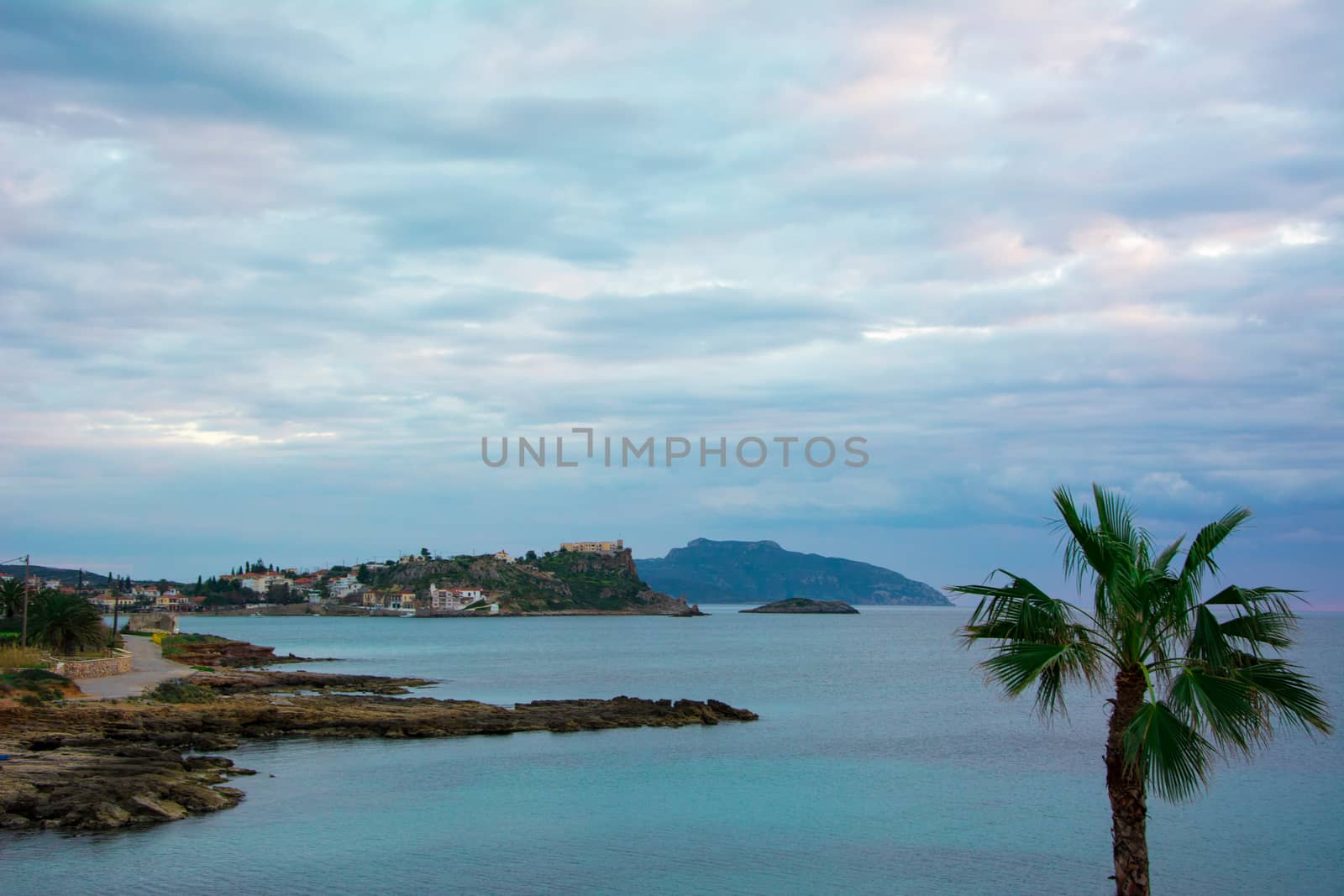 Nice Greek rocky beach with palm trees under a perfectly shaped cloudscape