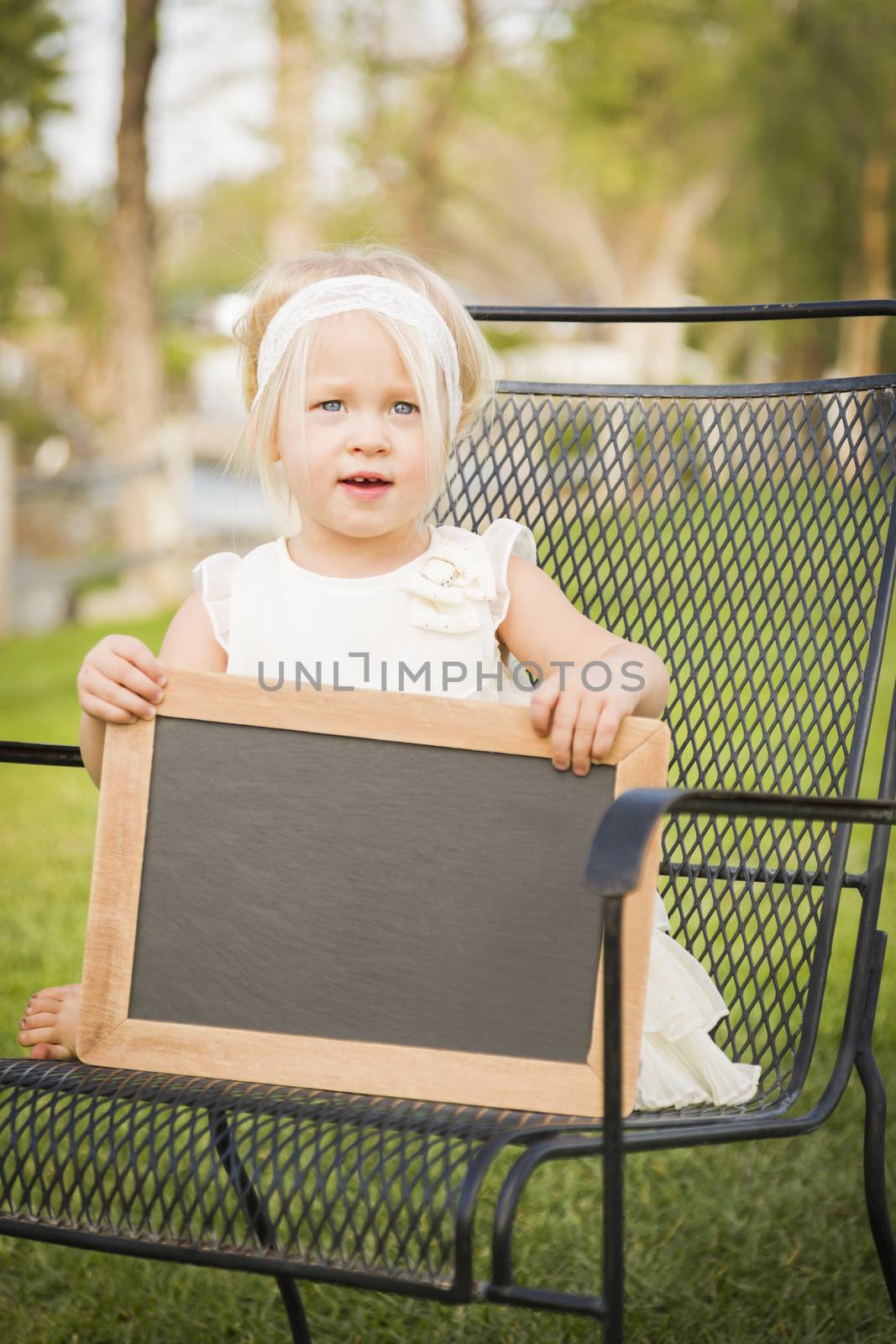 Cute Baby Girl Sitting in Chair Holding Blank Blackboard.