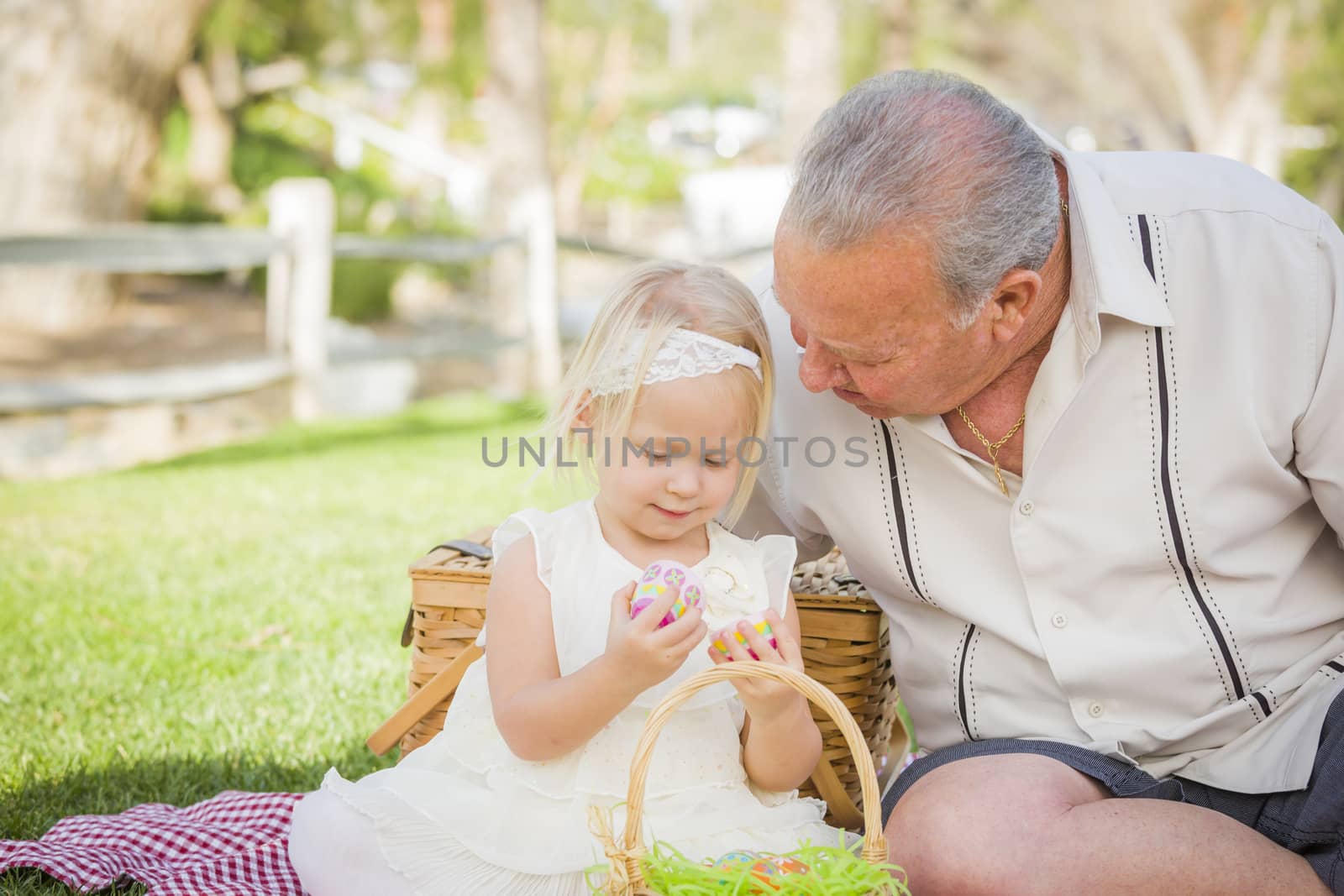 Loving Grandfather and Granddaughter Enjoying Easter Eggs on a Picnic Blanket At Park.