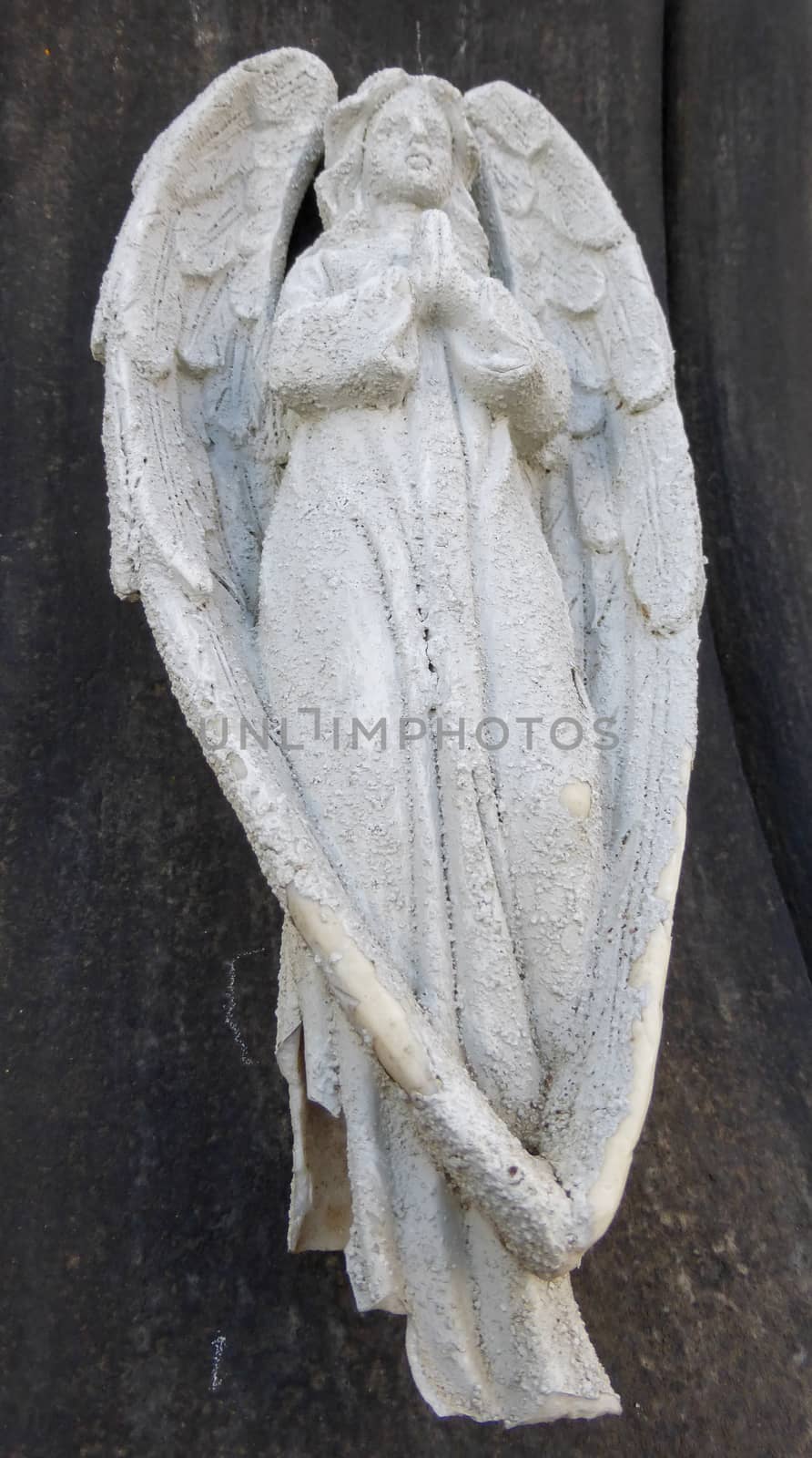Little white sculpture of praying angel on black background