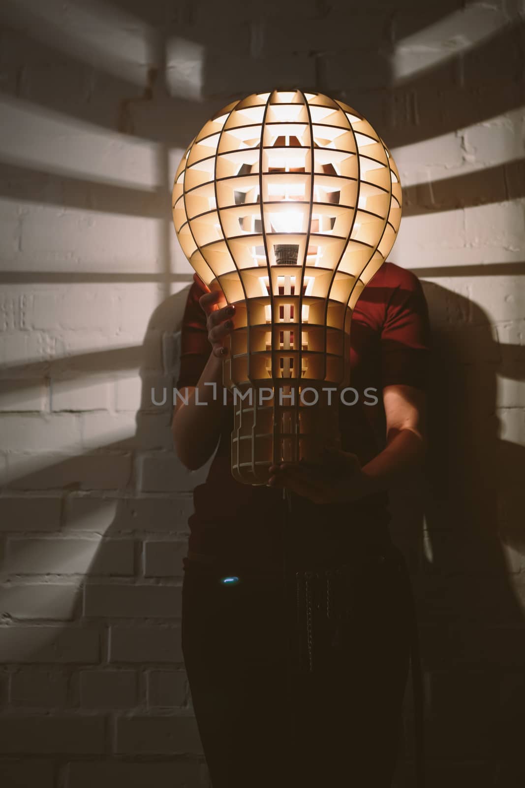 Hanging, wooden light shade lamp with bulb in hands