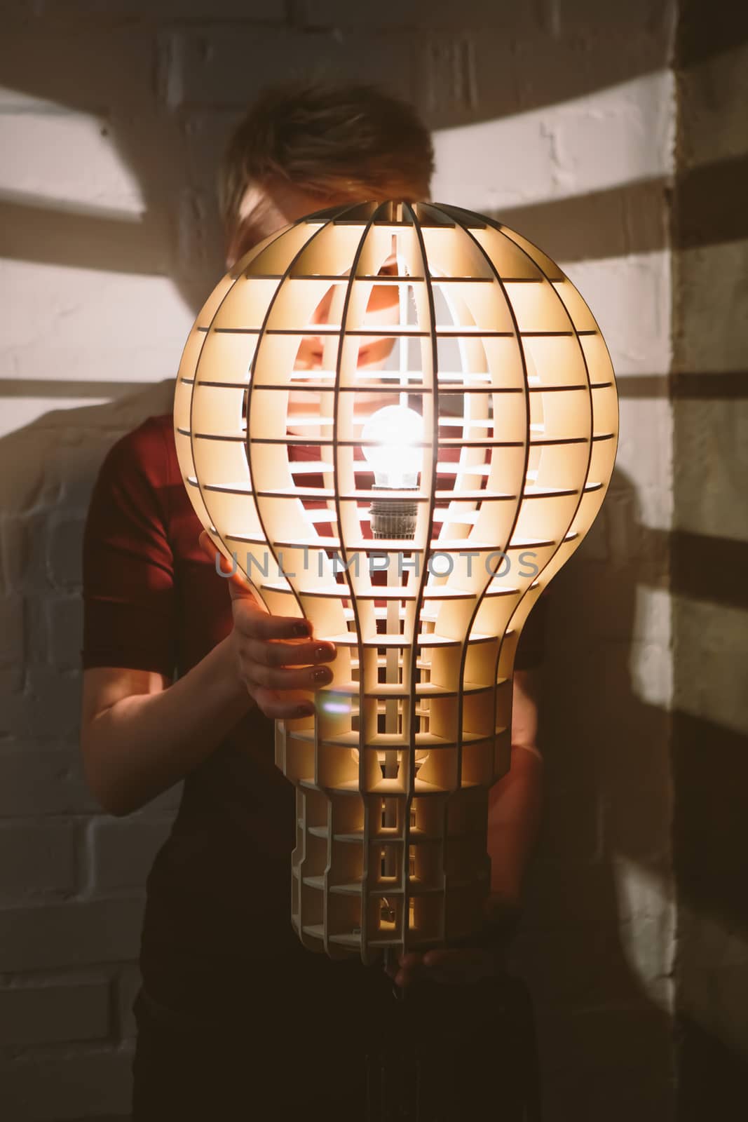 Hanging, wooden light shade lamp with bulb in hands