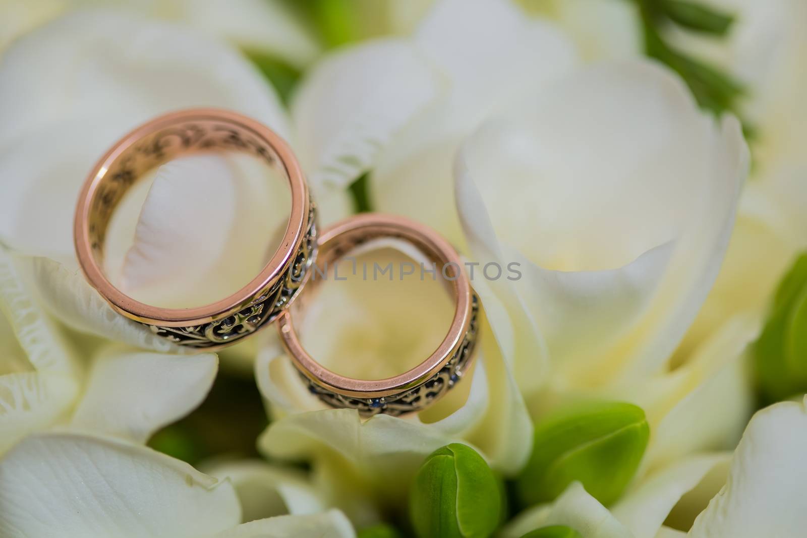 Two wedding rings in infinity sign with bouquet on black background. Love concept.