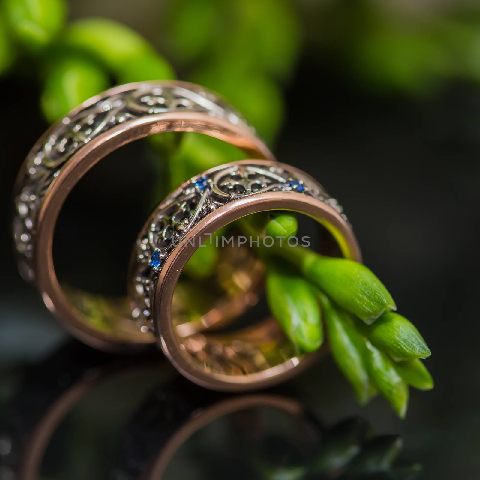 Two wedding rings in infinity sign with bouquet on black background. Love concept.