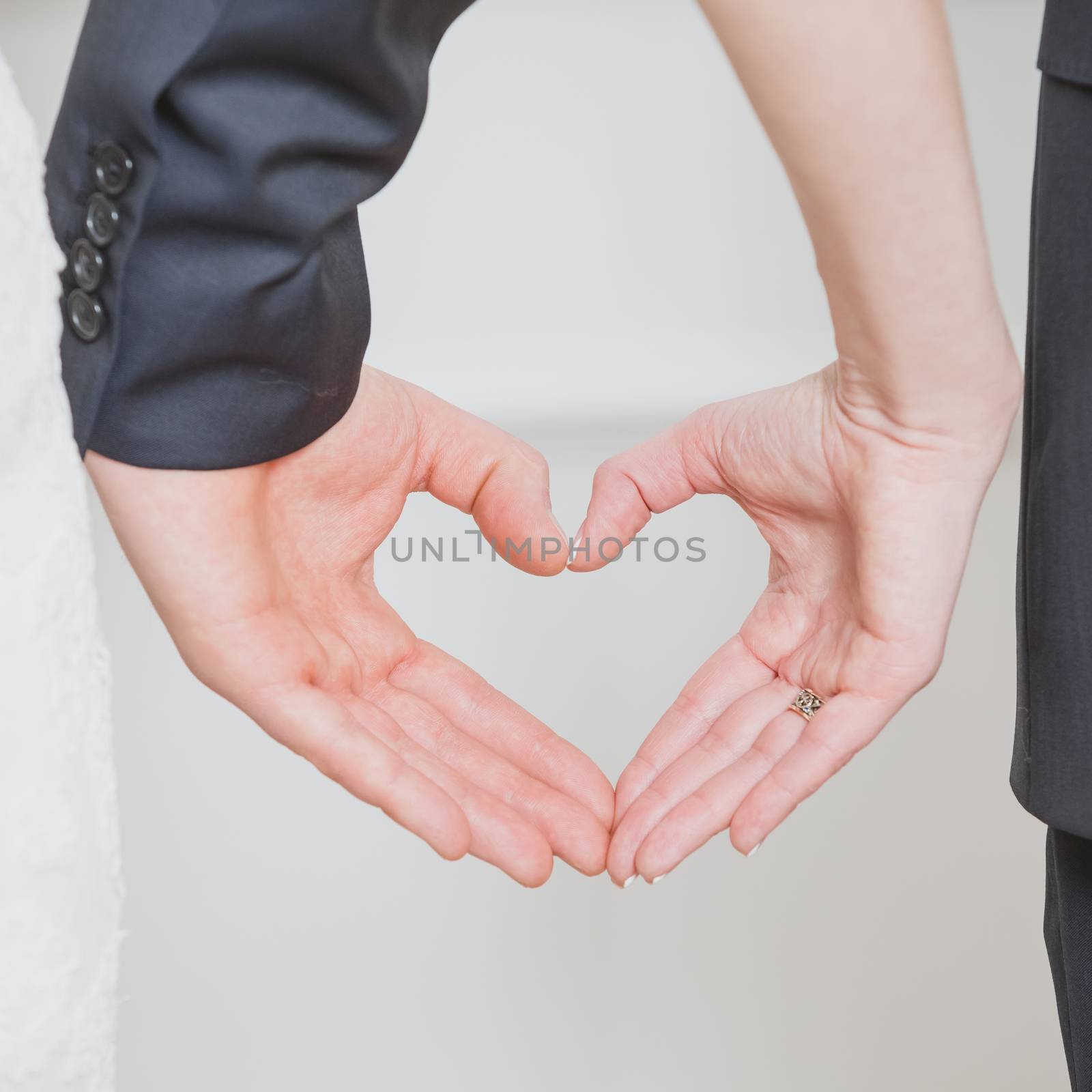 wedding couple showing shape of heart from their hands. by sarymsakov