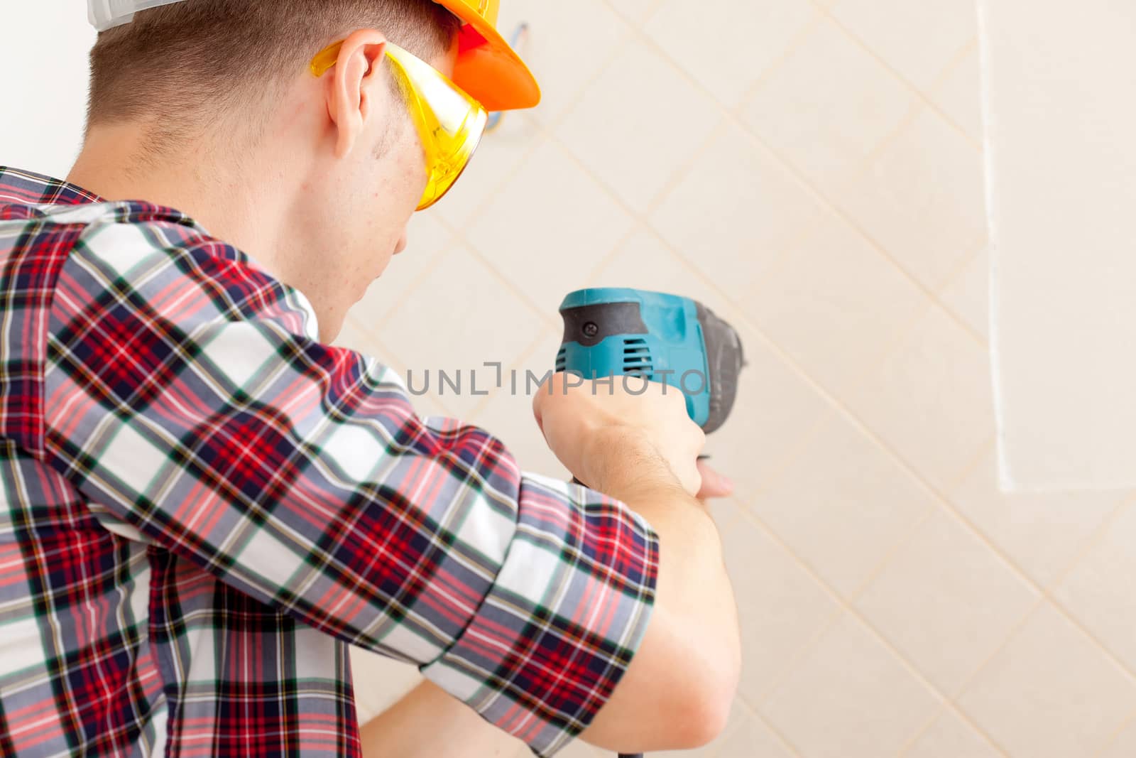 worker in protective gloves and eyeglasses with rock-drill