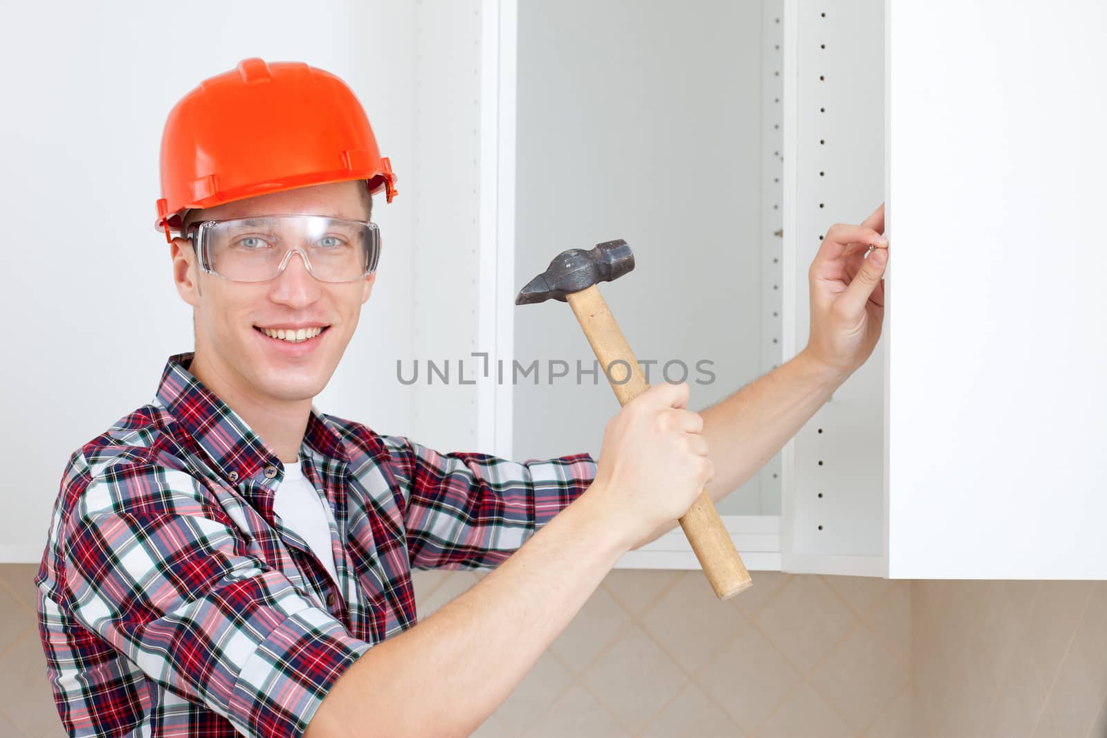 young worker with a hammer drives a nail