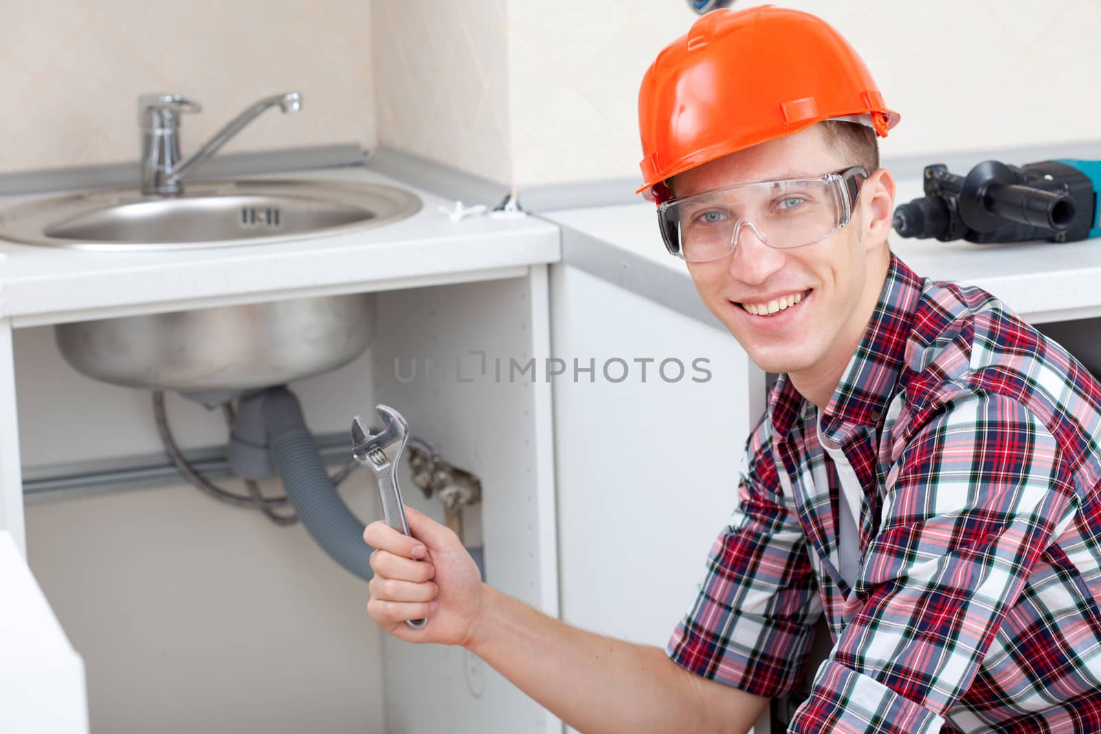 smiling plumber near the kitchen sink by Astroid