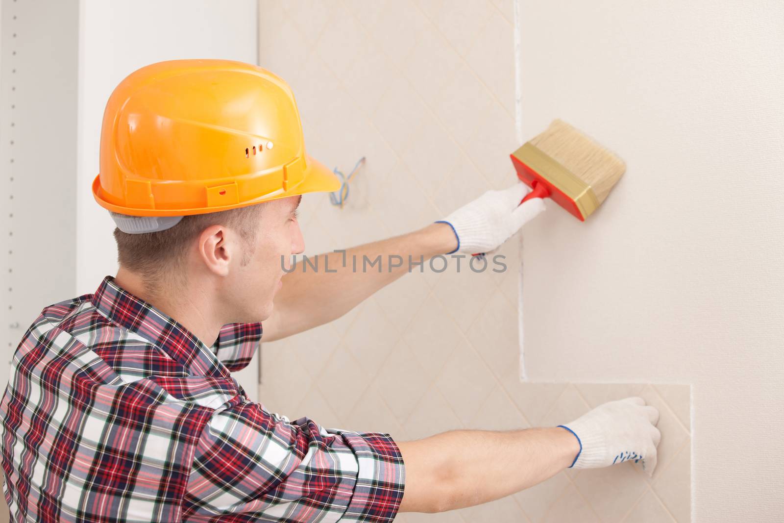 worker with paint brush prepares the wall for wallpapering