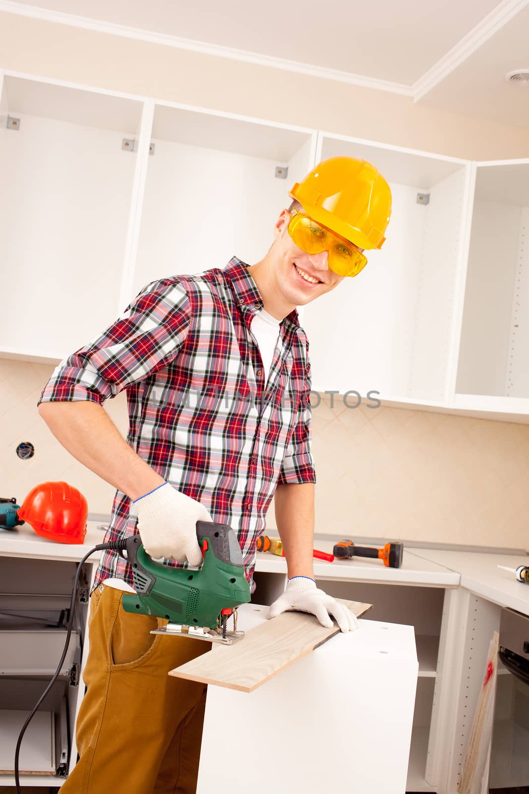 repairman works jigsaw in the interior of a new apartment