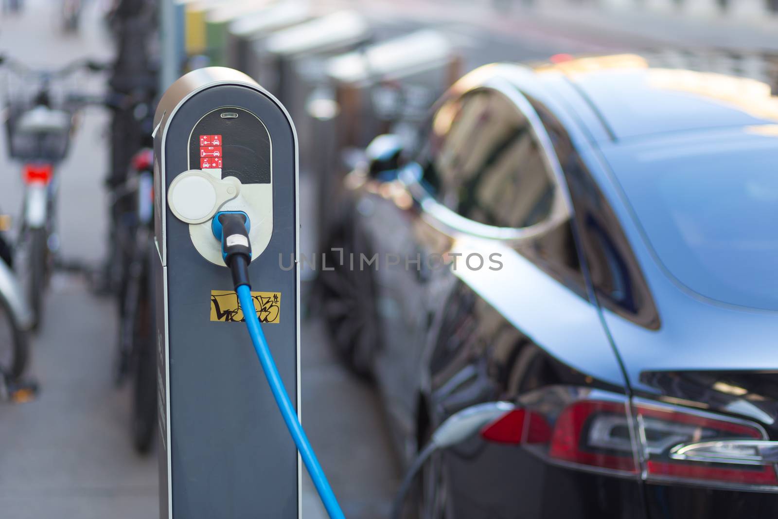 Power supply for electric car charging.  Electric car charging station. Close up of the power supply plugged into an electric car being charged.