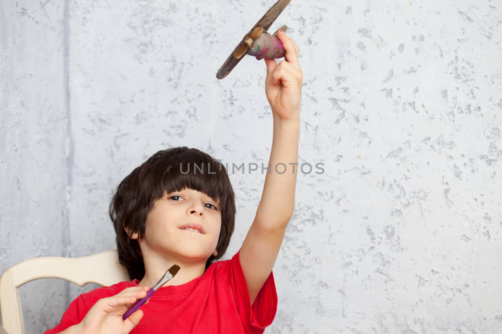 boy in a red shirt with a wooden plane and brush