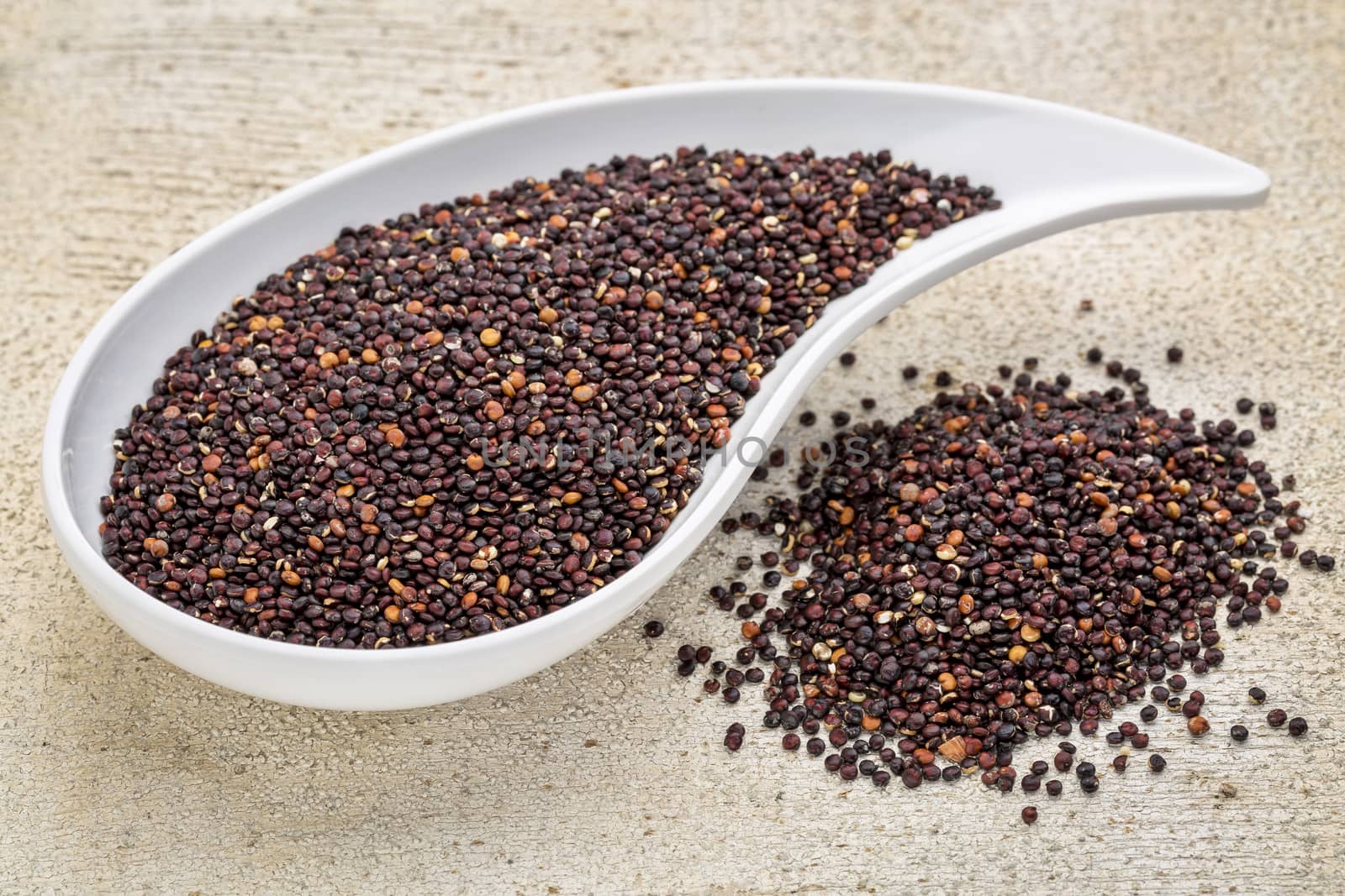 gluten free black quinoa grain grown iin Bolivia ,  a teardrop shaped bowl against white painted grunge wood