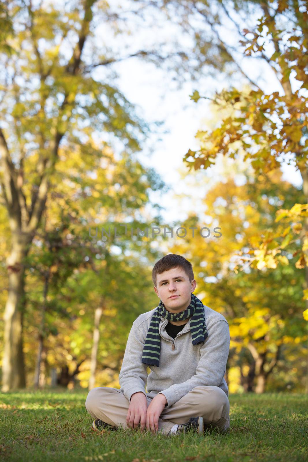Serious teenager with scarf sitting with crossed legs