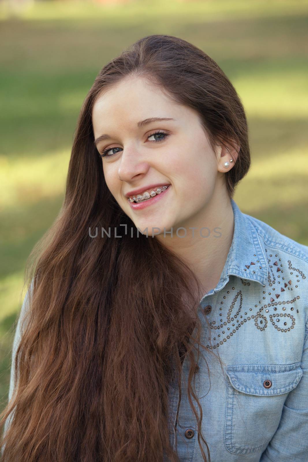 Caucasian teenager with long hair sitting outdoors