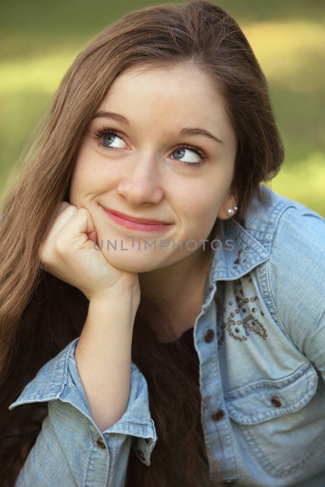 Close up of grinning woman with hand on chin looking up